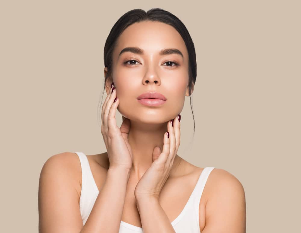 A woman with clear skin from SeruGlow treatments framing her face with her hands